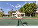 Exterior shot of a tennis court with a luxury home and manicured landscaping in the background at 7630 E Vaquero Dr, Scottsdale, AZ 85258