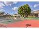 Exterior shot of a tennis court with a luxury home and tree in the background, under a cloudy sky at 7630 E Vaquero Dr, Scottsdale, AZ 85258