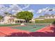 Exterior shot of a tennis court with a luxury home, landscaping, and large trees in the background at 7630 E Vaquero Dr, Scottsdale, AZ 85258