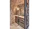 Unique wine cellar with stone walls, a decorative iron gate, and climate-controlled storage for wine bottles at 7630 E Vaquero Dr, Scottsdale, AZ 85258