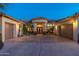 Stunning home with a circular driveway, meticulous landscaping, and a grand entrance, illuminated by soft lighting at 8427 E Preserve Way, Scottsdale, AZ 85266