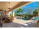 Covered patio with stone tile overlooks beautiful pool, palms, mature landscaping, and waterfall features at 8427 E Preserve Way, Scottsdale, AZ 85266