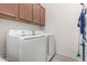 Efficient laundry room includes a front-load washer, dryer, and overhead cabinets at 8751 S 168Th Dr, Goodyear, AZ 85338