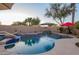 Lush pool area at dusk with rock waterfall, landscape lighting, and refreshing blue water at 950 E Desert Inn Dr, Chandler, AZ 85249
