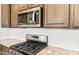 Close up of stainless steel microwave and stovetop with granite countertops and tile backsplash at 26949 W Lone Cactus Dr, Buckeye, AZ 85396