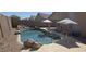 Backyard pool with rock waterfall feature, sunny patio, and umbrellas providing shade at 46148 W Tucker Rd, Maricopa, AZ 85139