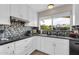 Modern kitchen with black countertops, white cabinets, and a window overlooking the backyard at 10543 E Sahuaro Dr, Scottsdale, AZ 85259