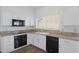 A bright, functional kitchen with white cabinets, granite countertops, and modern black appliances at 1248 E Briarwood Ter, Phoenix, AZ 85048