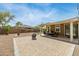 Expansive gravel backyard with a built-in fire pit, covered patio, grilling area, and mature trees at 18543 E Purple Sage Dr, Queen Creek, AZ 85142