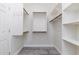 Bright walk-in closet featuring custom shelving, hanging rods, and gray tile flooring at 18575 E Pine Barrens Ave, Queen Creek, AZ 85142