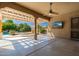 Covered outdoor patio with ceiling fan and TV, overlooking a tranquil pool and lush landscaping at 18575 E Pine Barrens Ave, Queen Creek, AZ 85142