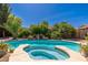 Beautiful backyard pool with rock features, lush landscaping, and relaxing spa area at 18575 E Pine Barrens Ave, Queen Creek, AZ 85142