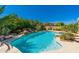 Lush backyard with a swimming pool, rock waterfall feature, and tropical landscaping creating a serene oasis at 18575 E Pine Barrens Ave, Queen Creek, AZ 85142
