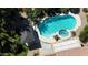 Aerial view of a backyard pool with baja step and jacuzzi spa, shaded pergola, and lush landscaping at 18575 E Pine Barrens Ave, Queen Creek, AZ 85142
