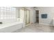 Bright bathroom featuring a glass block window, soaking tub, tiled floor, and separate shower at 2698 E Carla Vista Dr, Gilbert, AZ 85295