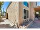 Side exterior of a two-story home featuring stucco siding, trimmed windows and a charming garden bed at 4050 W Camino Del Rio --, Glendale, AZ 85310