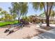 Community playground area with climbing wall, seesaw, covered seating, and mature trees at 4176 E Bonanza Rd, Gilbert, AZ 85297