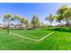 Community volleyball court with lush green lawn, mature trees, and nearby residences at 4176 E Bonanza Rd, Gilbert, AZ 85297