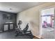 Home gym features stationary bicycle, TV, rubber flooring, and view into a playroom at 44235 W Mcclelland Dr, Maricopa, AZ 85138