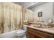 Traditional bathroom featuring a shower-tub, vanity with framed mirror and floral printed curtain at 5741 W Purdue Cir, Glendale, AZ 85302