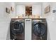 Modern laundry room with front-loading washer and dryer, white cabinets, and wooden accents at 601 E Winter Dr, Phoenix, AZ 85020