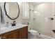 Well-lit bathroom with a stylish vanity, framed mirror and a walk-in shower with unique pebble flooring at 6209 E Bramble Berry Ln, Cave Creek, AZ 85331