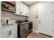 Convenient laundry room featuring modern machines, a sink, ample storage and wooden shelving at 6209 E Bramble Berry Ln, Cave Creek, AZ 85331