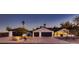 Charming home with three car garage, mature landscaping, and a well manicured front yard at dusk at 8755 E Gary Rd, Scottsdale, AZ 85260