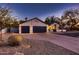 Charming home with three car garage, mature landscaping, and a well manicured front yard at dusk at 8755 E Gary Rd, Scottsdale, AZ 85260