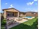 Inviting backyard with a pool, lush lawn, comfortable seating, and a cozy outdoor fireplace feature at 22131 E Estrella Rd, Queen Creek, AZ 85142