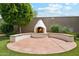 Backyard featuring an outdoor fireplace, surrounding seating, mature trees, and lush green grass at 18001 W Cassia Way, Goodyear, AZ 85338