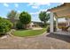 Landscaped backyard with a fireplace, patio, artificial grass, trees, and a gravel area at 18001 W Cassia Way, Goodyear, AZ 85338
