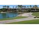 A sidewalk curves around a lake and toward the clubhouse with palm trees in the background at 18001 W Cassia Way, Goodyear, AZ 85338