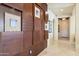 Hallway with decorative wood paneling and views of archways, a white door, and tile flooring at 18001 W Cassia Way, Goodyear, AZ 85338