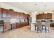 Spacious kitchen boasts stone floors, wooden cabinets, stainless appliances, an island, and chairs at 18001 W Cassia Way, Goodyear, AZ 85338