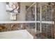 Main bathroom featuring soaking tub, glass-enclosed shower with custom tile work, and decorative art at 18001 W Cassia Way, Goodyear, AZ 85338