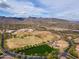 This aerial shows a spacious city park with baseball fields, playground, and a lush green area, with mountains in the background at 2305 N Heritage St, Buckeye, AZ 85396