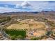 This aerial shows a large community park with baseball fields, playground, and mountain views in the distance under a sunny sky at 2305 N Heritage St, Buckeye, AZ 85396