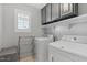 Modern laundry room featuring white washer and dryer, and gray cabinetry at 2305 N Heritage St, Buckeye, AZ 85396
