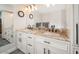 Bathroom with double sinks, granite countertop, white cabinets, and two clocks on the wall at 4303 E Cactus Rd # 407, Phoenix, AZ 85032
