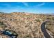 Expansive desert landscape view with native vegetation and scenic road winding through the property at 11130 E Rolling Rock Dr, Scottsdale, AZ 85262