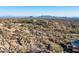 Desert landscape with mountains in the distance, native vegetation, and a road curving through the property at 11130 E Rolling Rock Dr, Scottsdale, AZ 85262
