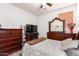 A comfortable bedroom with wood flooring, dark wood furniture, a flat screen TV, and a window at 12033 W Davis Ln, Avondale, AZ 85323