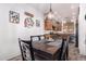 Elegant dining area with a stylish chandelier, wine-themed decor, and access to the kitchen at 12033 W Davis Ln, Avondale, AZ 85323