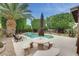 Backyard view with large stone table, covered umbrella, and pool with calming waterfall feature at 15962 W Statler St, Surprise, AZ 85374