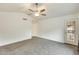 Bright, spacious living room featuring neutral carpet, ceiling fan and white walls at 17514 N Rainbow Cir, Surprise, AZ 85374