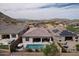 Aerial view of backyard featuring a pool, spa, covered patio, and mountain views at 18233 W Hope Dr, Goodyear, AZ 85338
