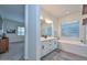 Bright bathroom with double vanity, soaking tub, textured tile, and separate glass shower near bedroom at 18233 W Hope Dr, Goodyear, AZ 85338