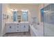 Bright bathroom with a double vanity, soaking tub, and natural light from large window at 18233 W Hope Dr, Goodyear, AZ 85338