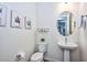 Stylish powder room features a pedestal sink, modern fixtures, and desert-themed art at 18233 W Hope Dr, Goodyear, AZ 85338